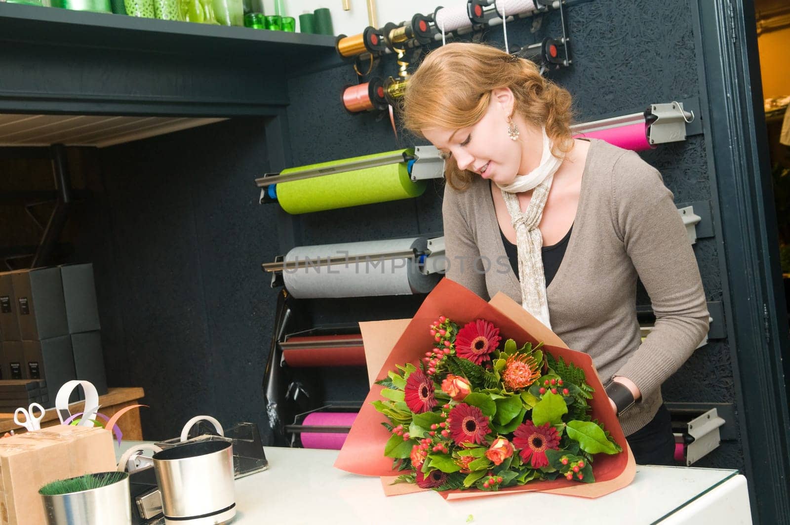 Female florist working in a flower store, making the bouquet ready for the customer