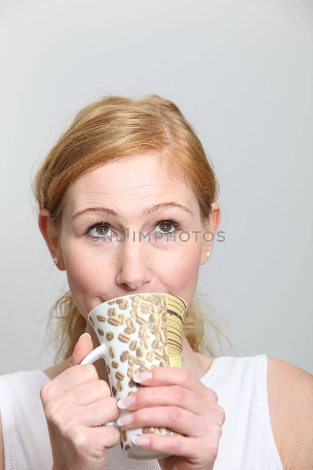 Young woman enjoying her coffee and looking up - vertically