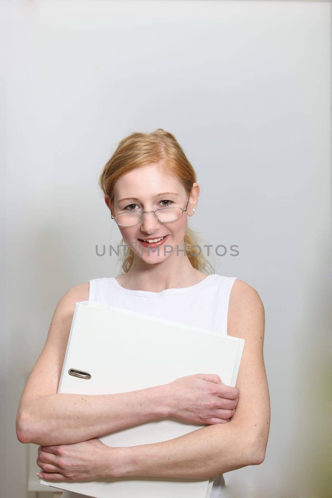 Pretty woman in the office. She holds a file folder in her hands - portrait format