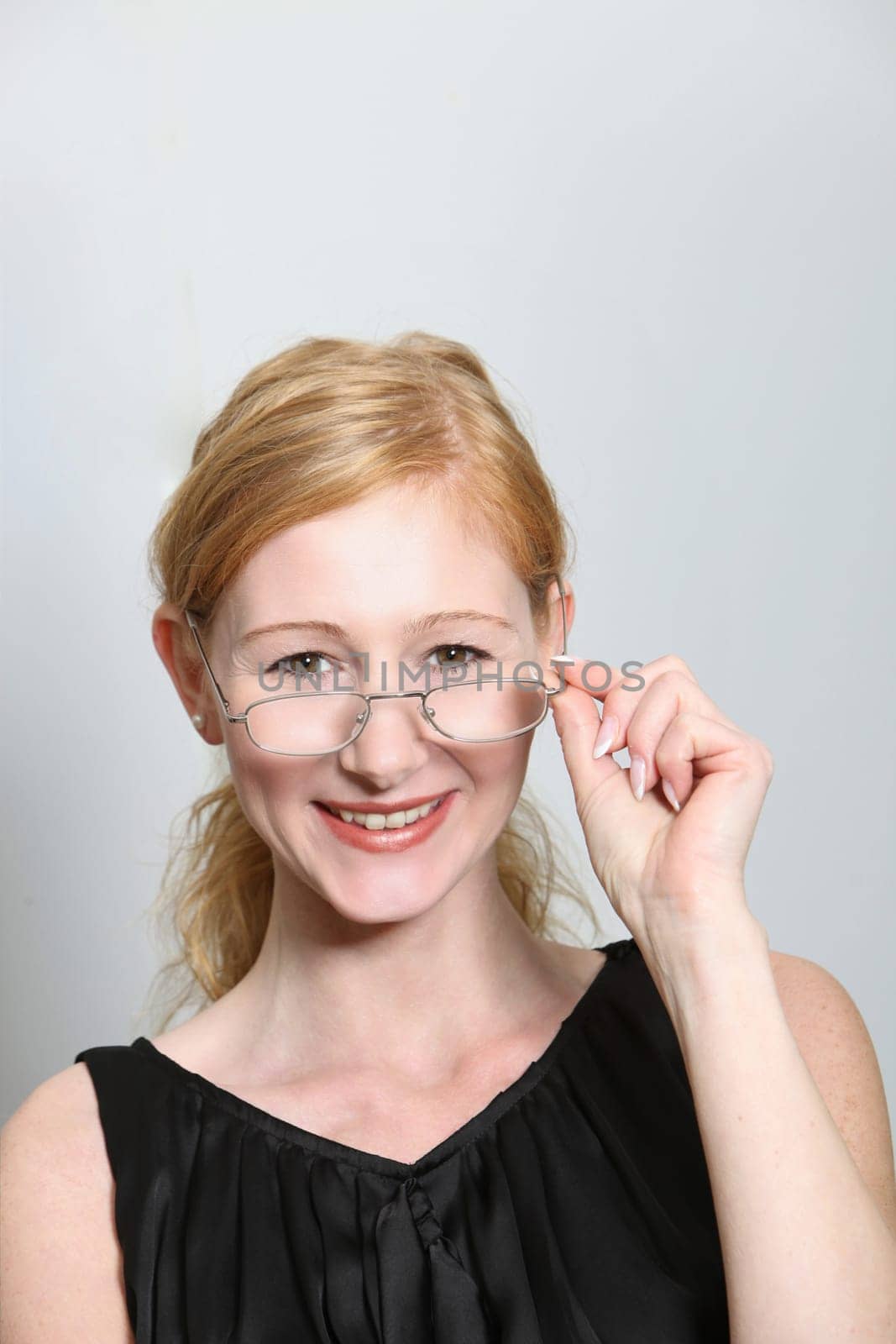 Young woman laughing looking over the rim of glasses - vertically
