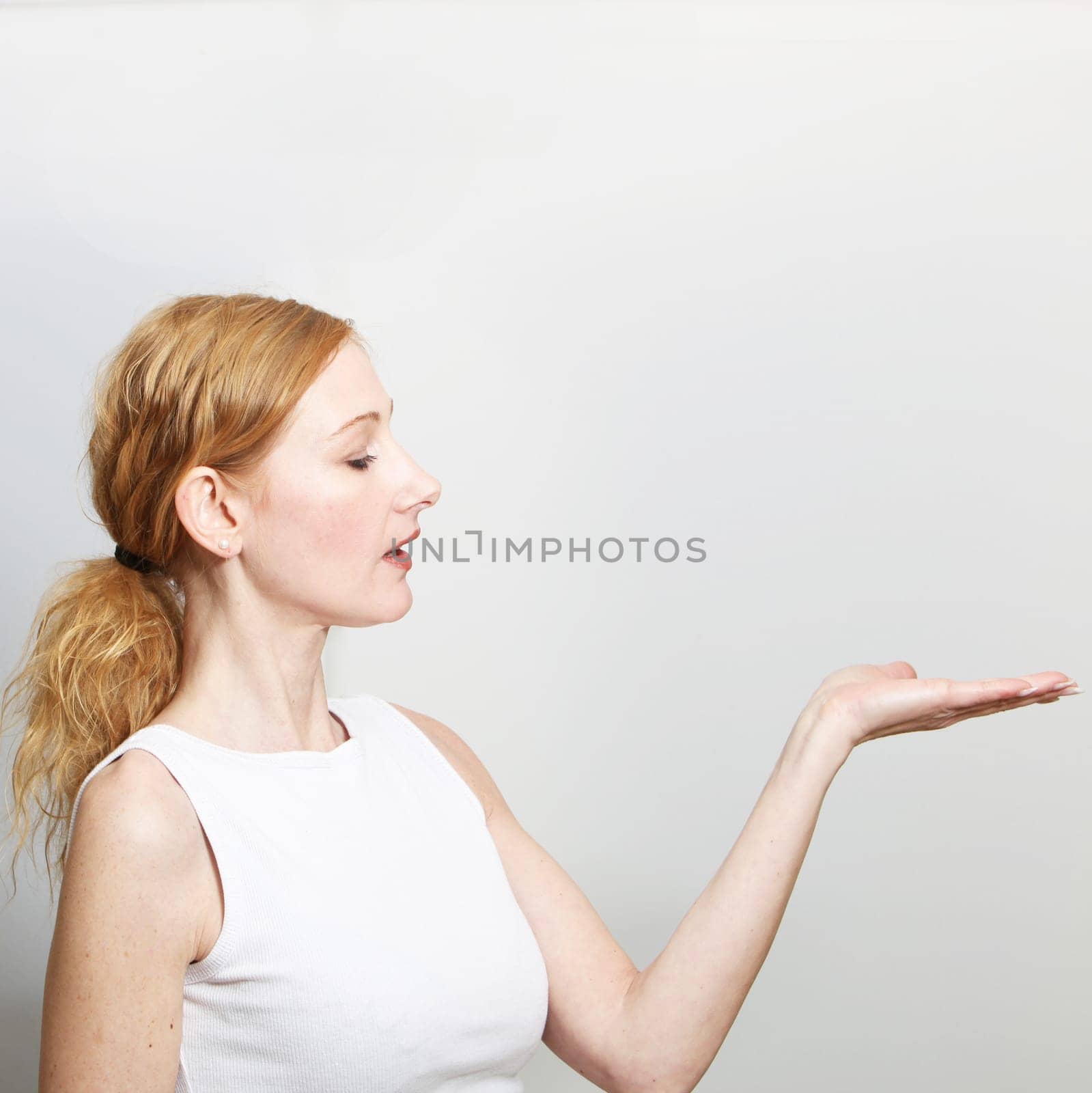 Woman presents something on her hand - with copy space. She looks at her hand.- Square
