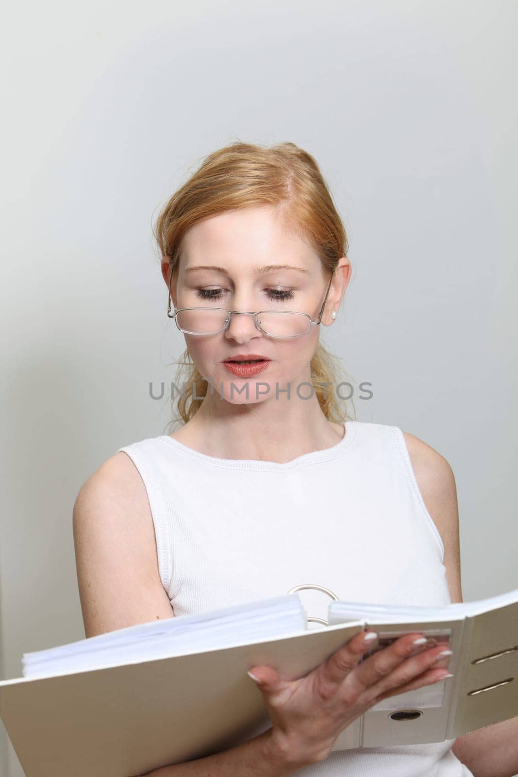 Young woman in the office looking at her documents. She wears glasses - portrait format