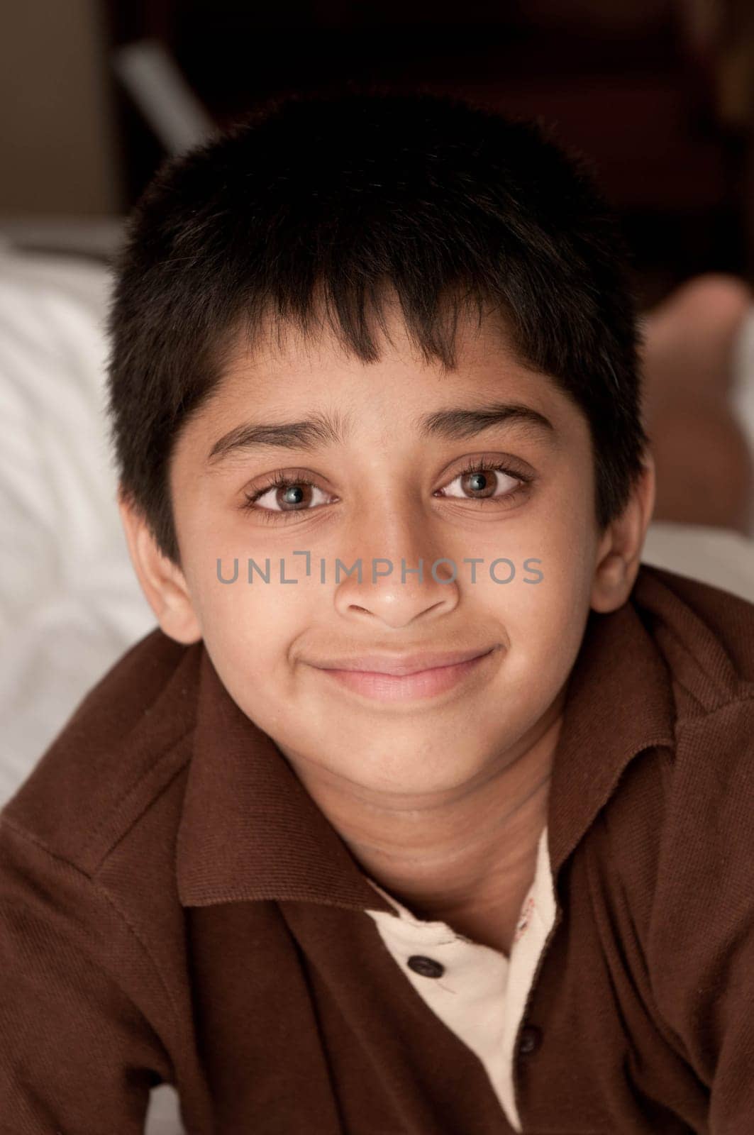 Handsome Indian kid lying happily on the bed
