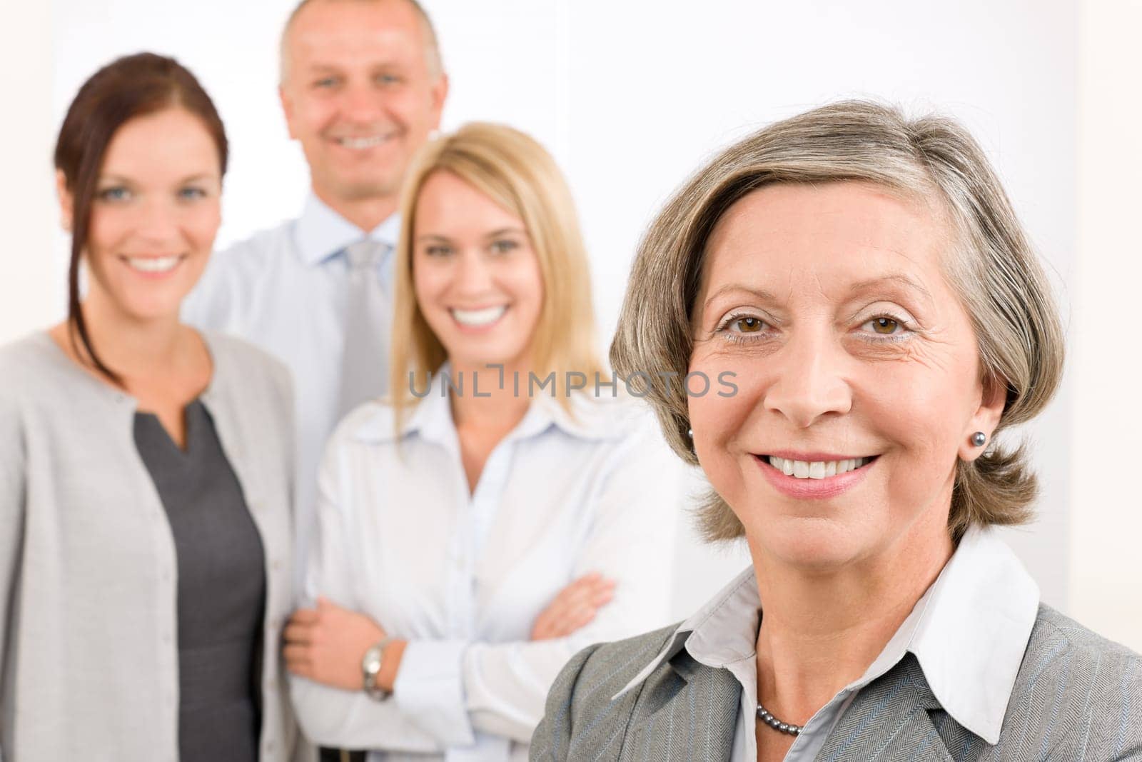 Business team senior businesswoman with attractive happy colleagues in office