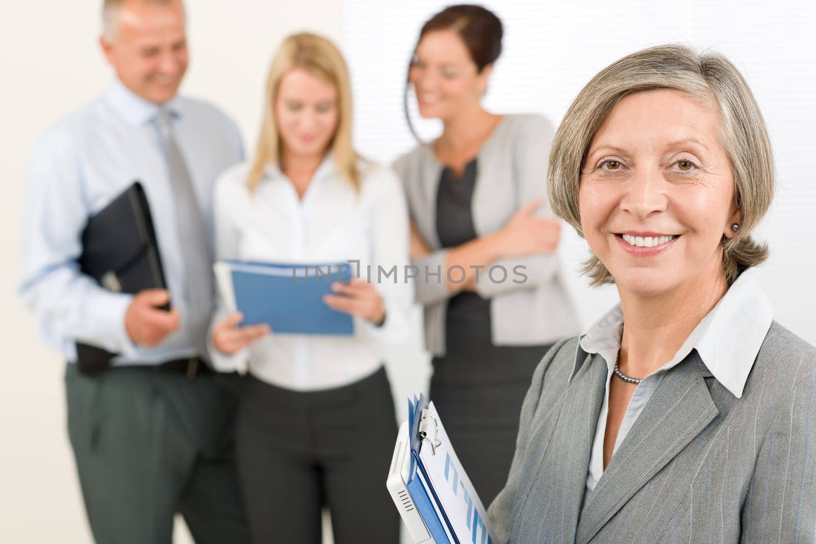 Business team senior businesswoman in front with attractive happy colleagues
