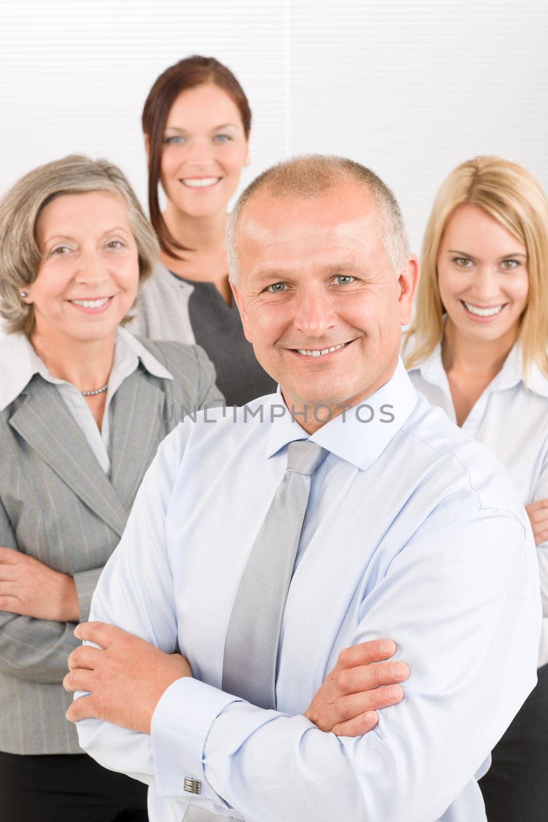 Business team senior businessman with attractive happy colleagues in office
