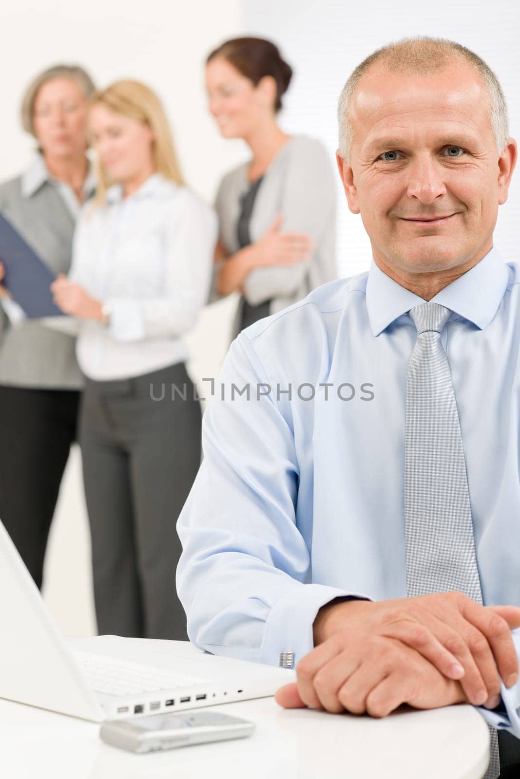 Business team happy mature businessman with attractive colleagues looking file