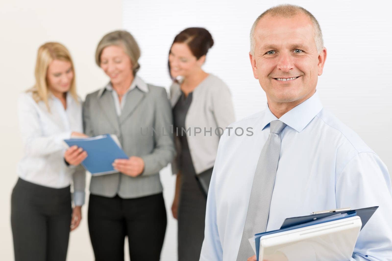 Business team senior businessman in front with attractive happy colleagues