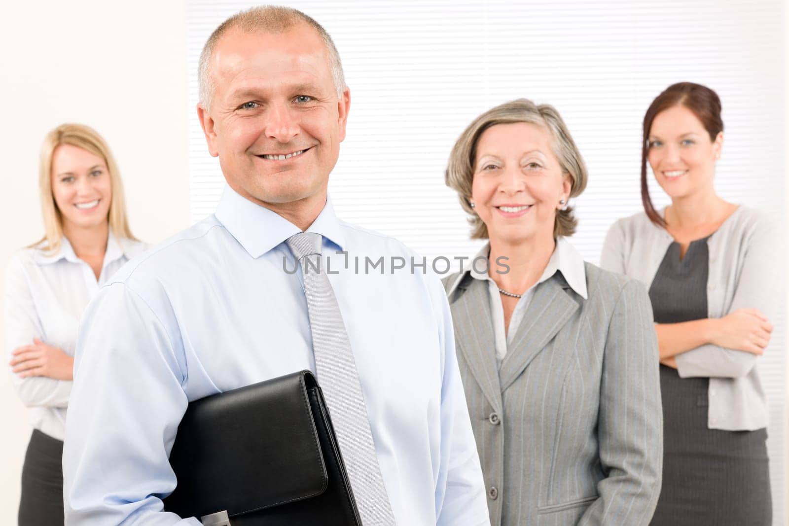 Business team mature businessman with attractive happy colleagues in office