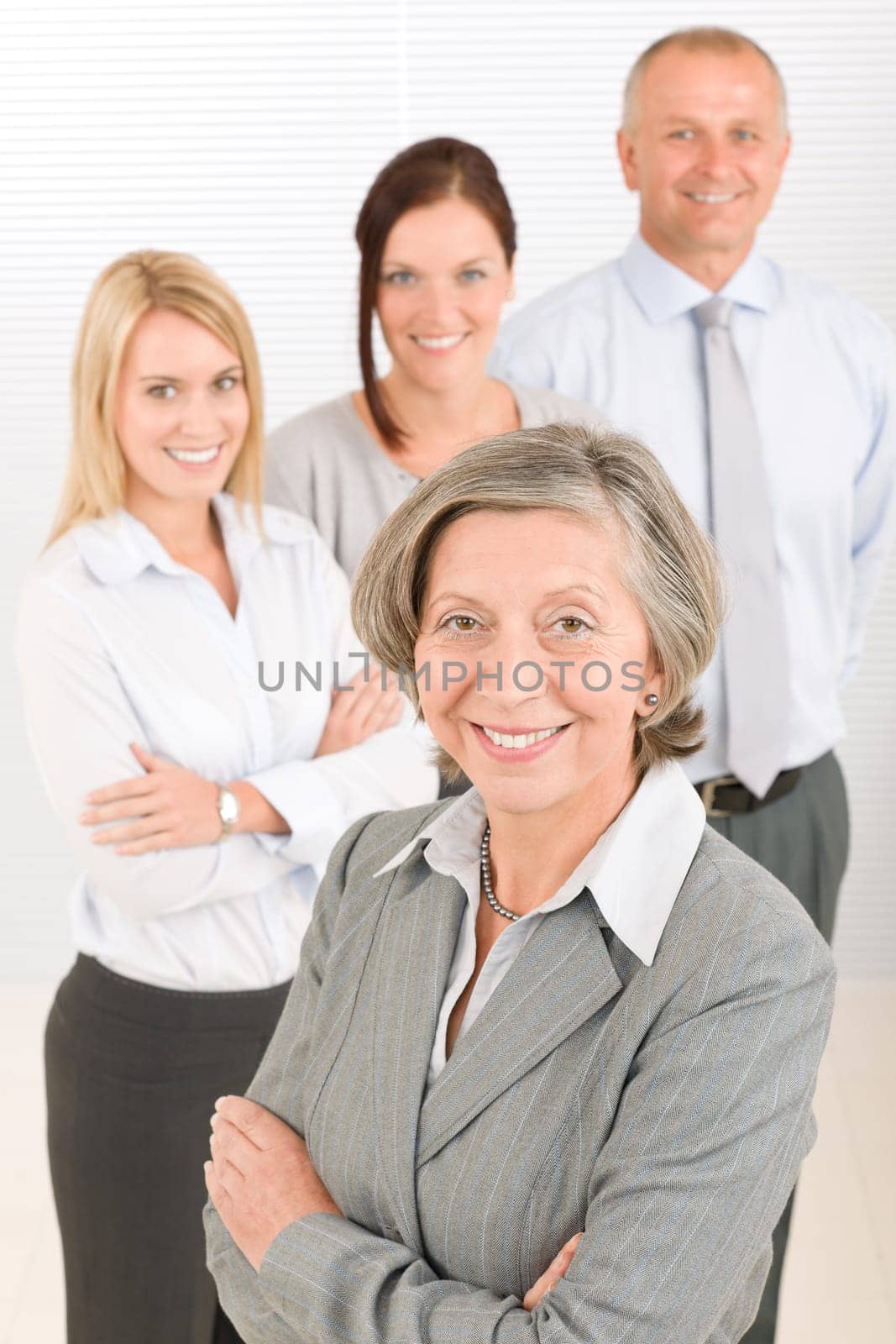Business team senior businesswoman with attractive happy colleagues in office