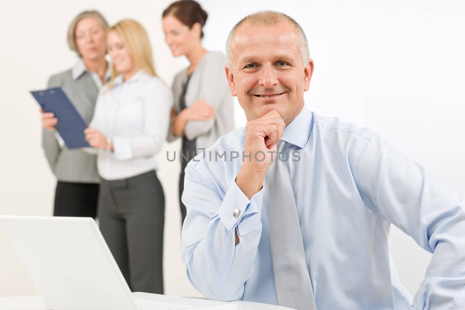 Business team happy mature businessman with attractive colleagues looking file