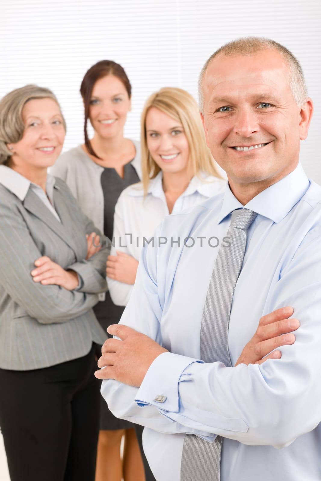Business team senior businessman with attractive happy colleagues in office