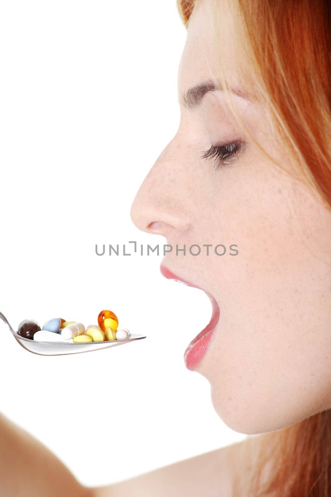Teen beautiful caucasian girl taking pills from spoon over white background.