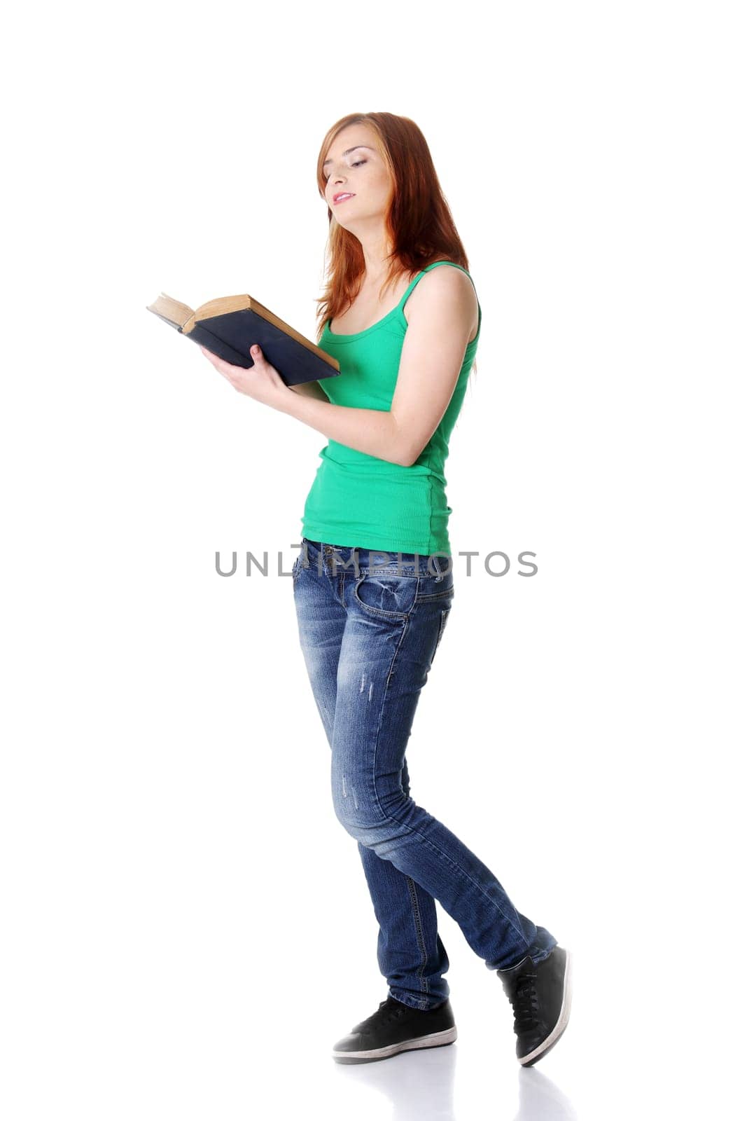 Pretty standing caucasian teen girl reading a book. Isolated on white.