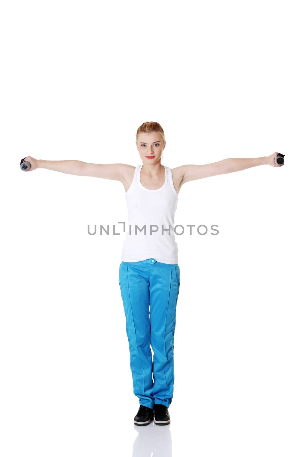 Teen pretty standing caucasian girl holding dumbbells doing exercise.
