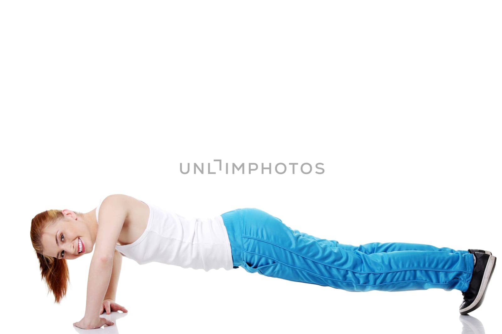 Pretty teen caucasian girl doing exercises on the floor over white background.
