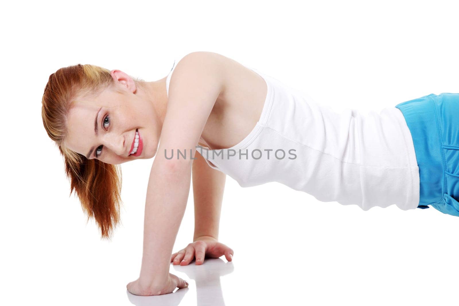 Pretty teen caucasian girl doing exercises on the floor over white background.