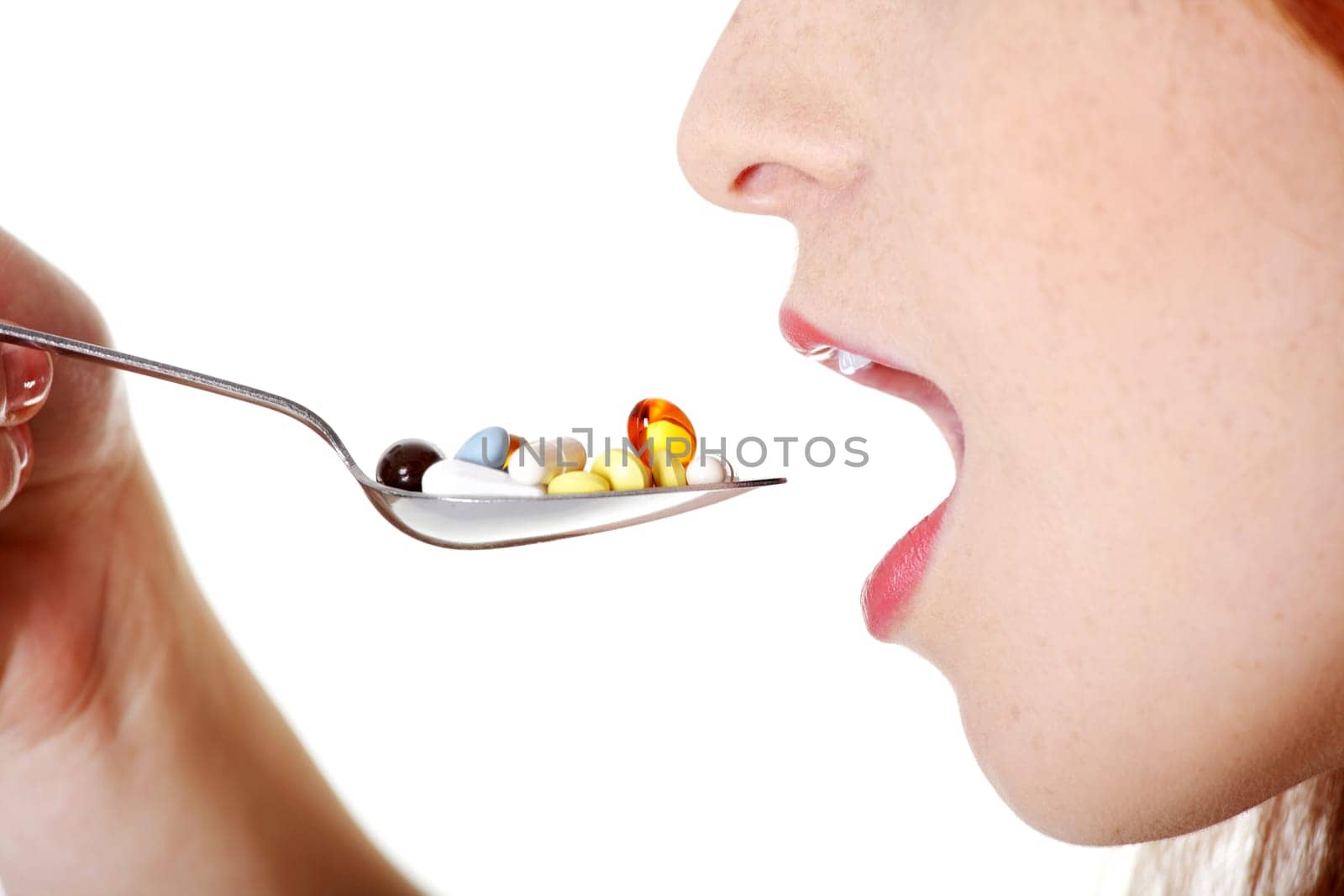 Closeup on teen caucasian girl`s open mouth taking pills from spoon.