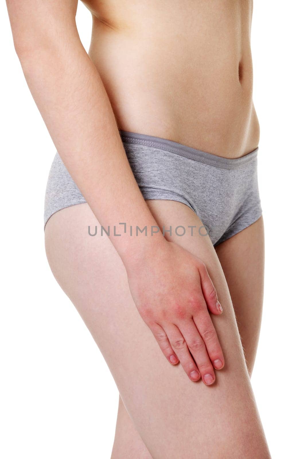 Site view of a fit young girl holding a hand on her sexy thigh, dressed in gray underwear, isolated on white beckground.
