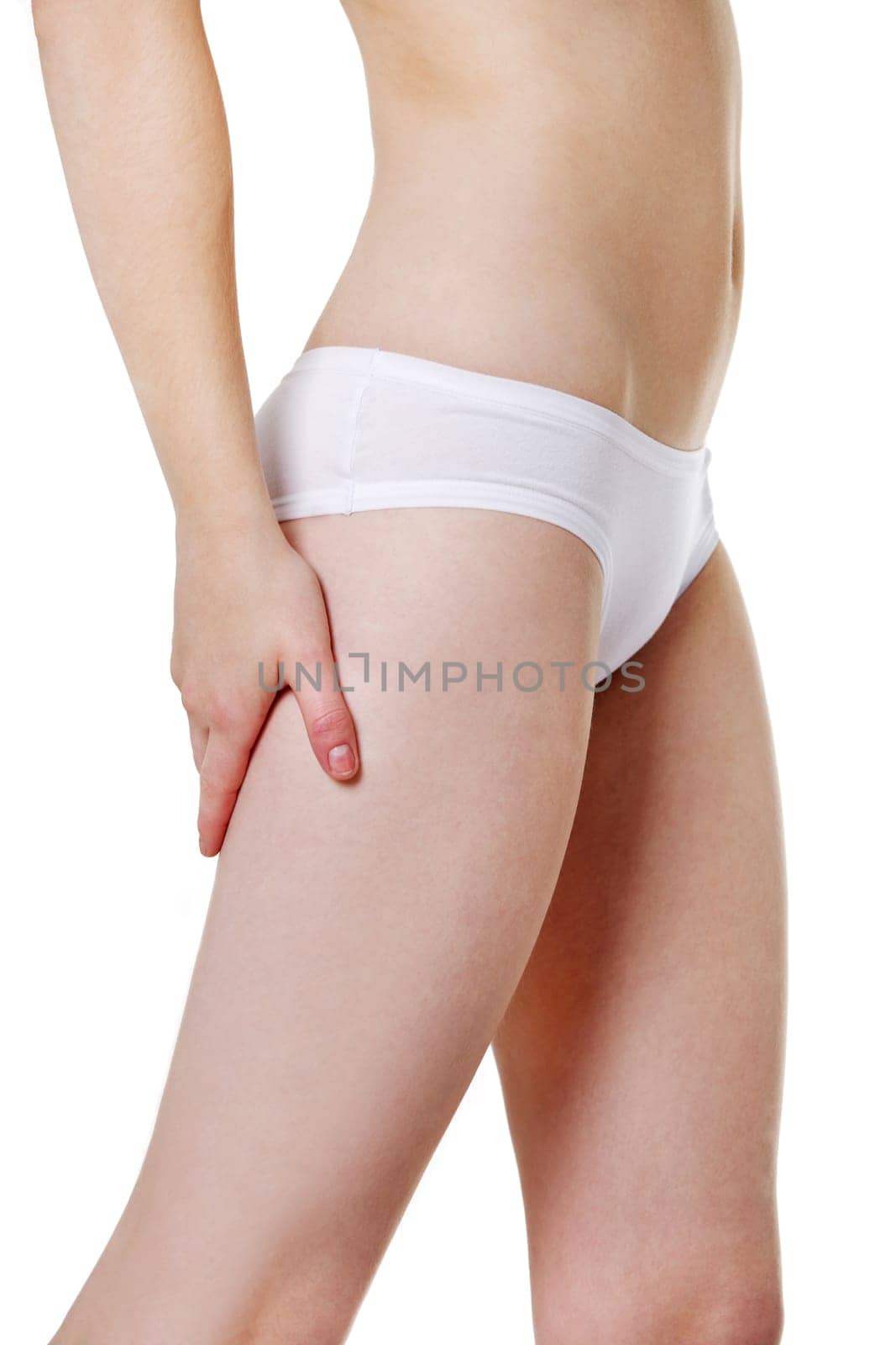 Site view of a fit young girl holding a hand on her sexy thigh, dressed in white underwear, isolated on white beckground.