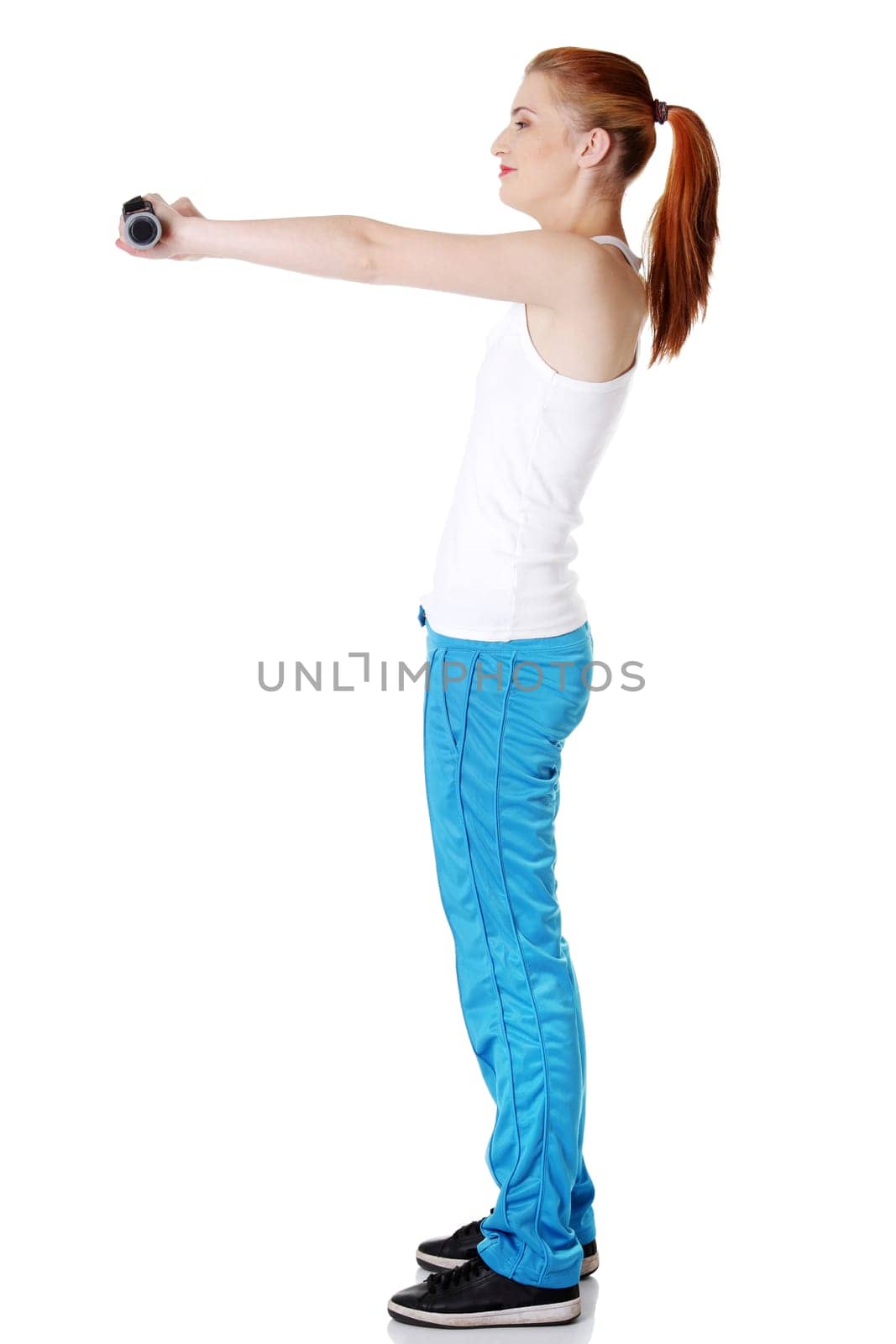 Teen pretty standing caucasian girl holding dumbbells doing exercise.