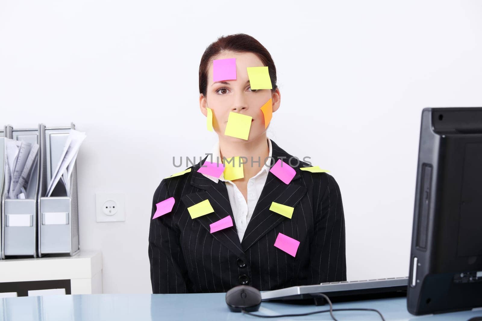 Beautiful caucasian businesswoman sitting in the office with post it notes on her body.