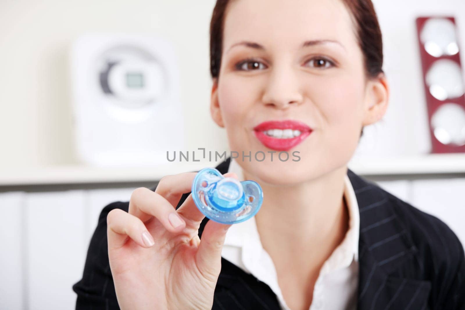 Pretty caucasian businesswoman giving a baby`s dummy to her child.