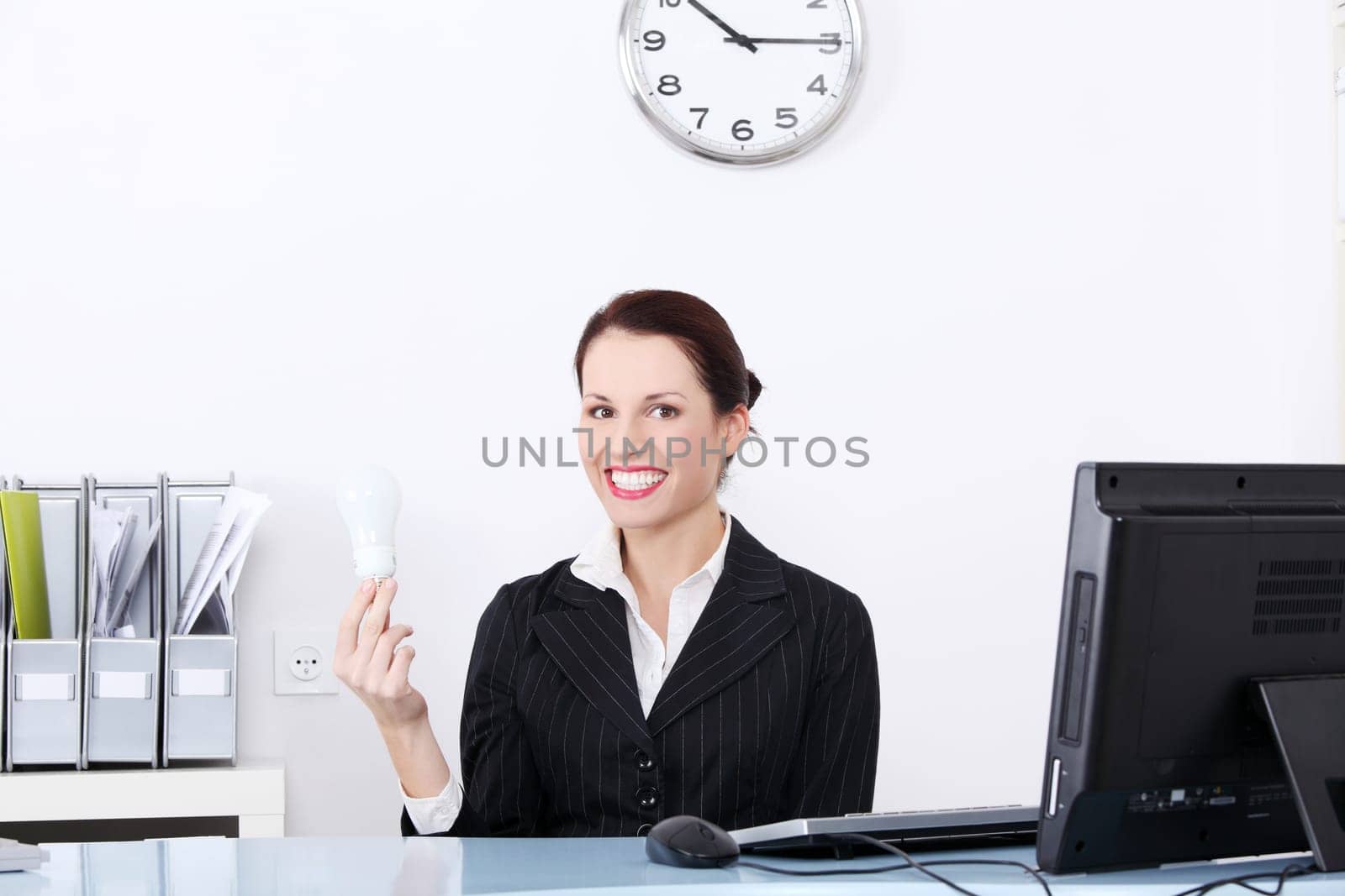 Pretty caucasian businesswoman holding a light bulb in the office.