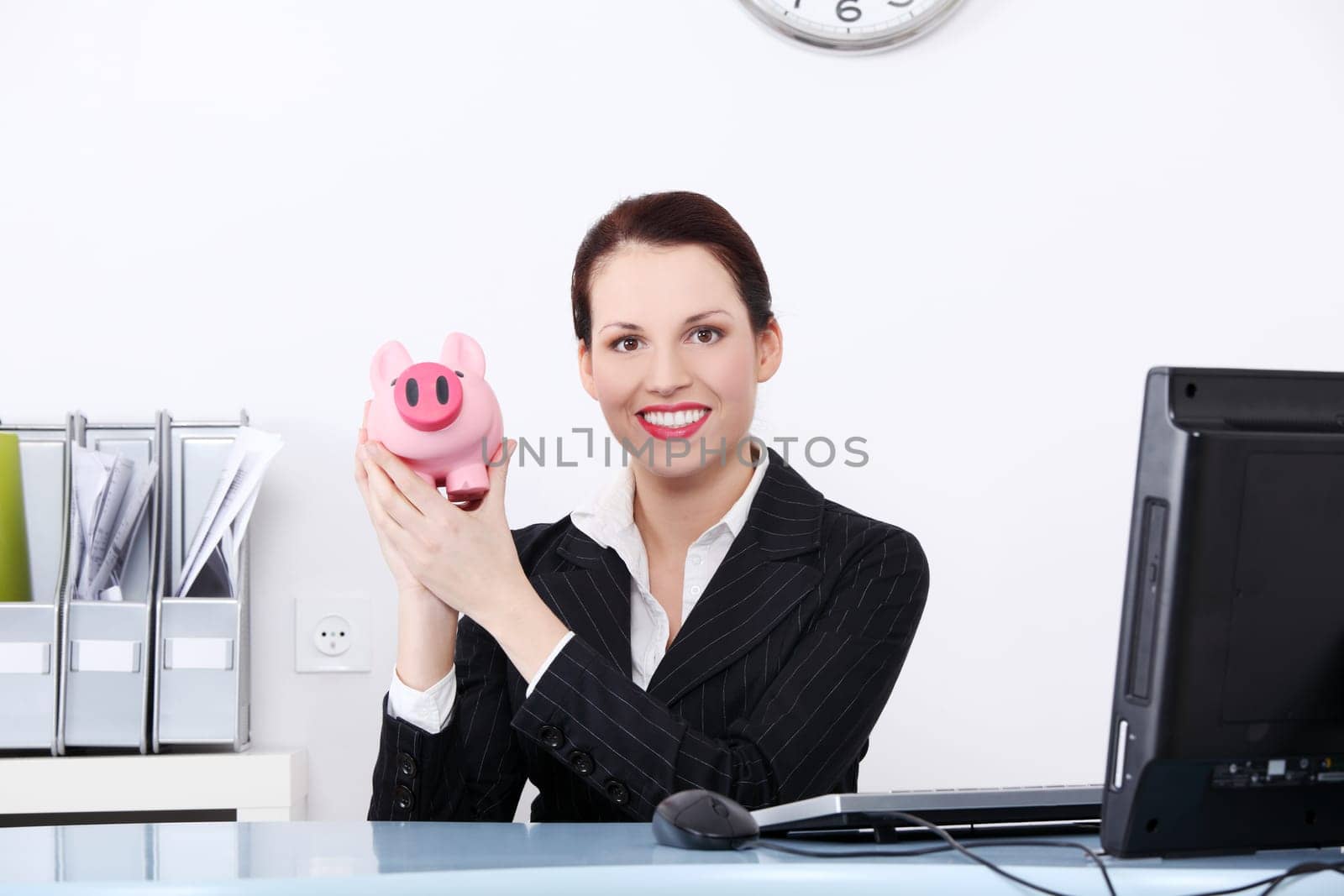 Pretty caucasian businesswoman holding piggy bank in the office.