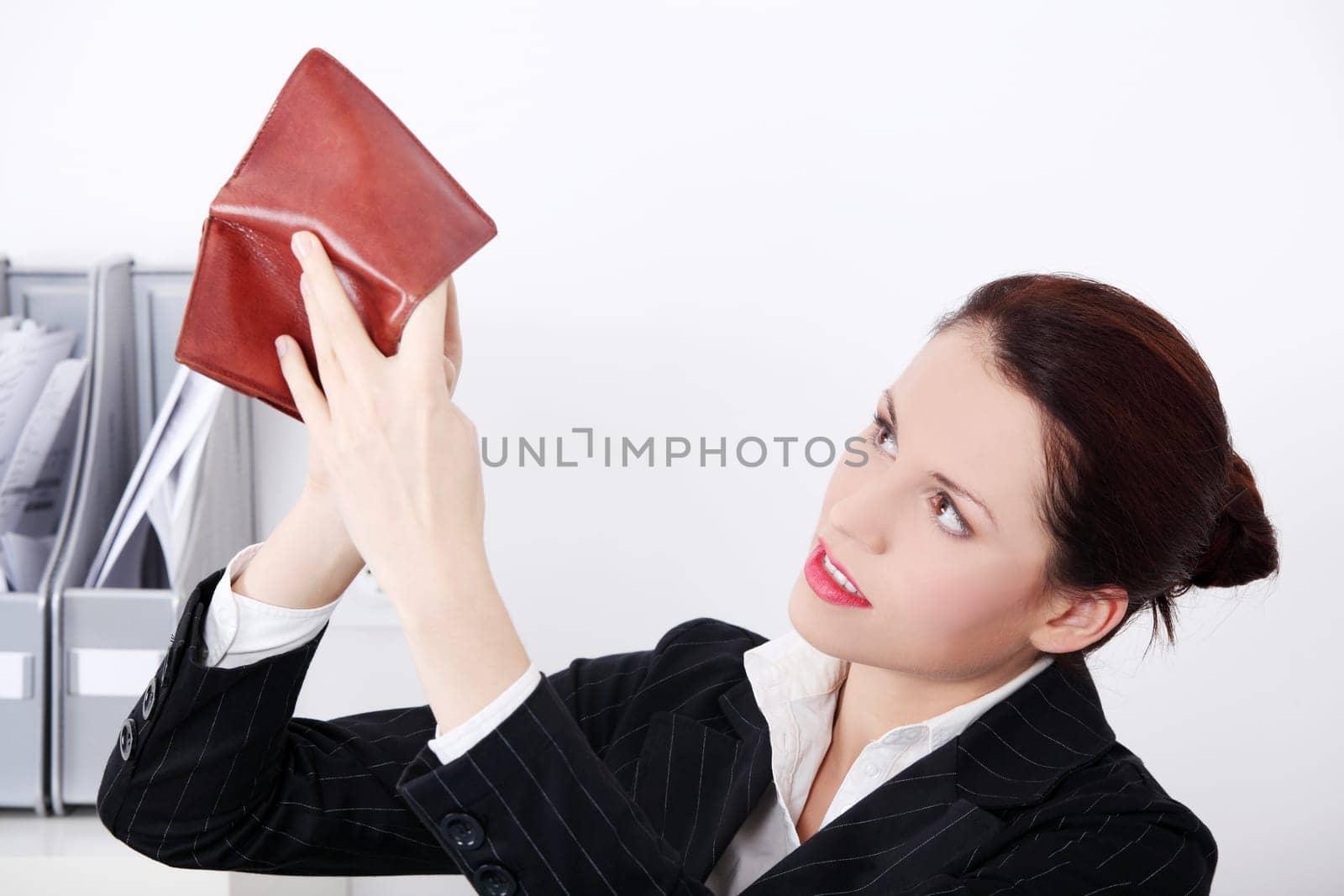 Pretty caucasian businesswoman sitting in the office looking at her empty pocket in the office.