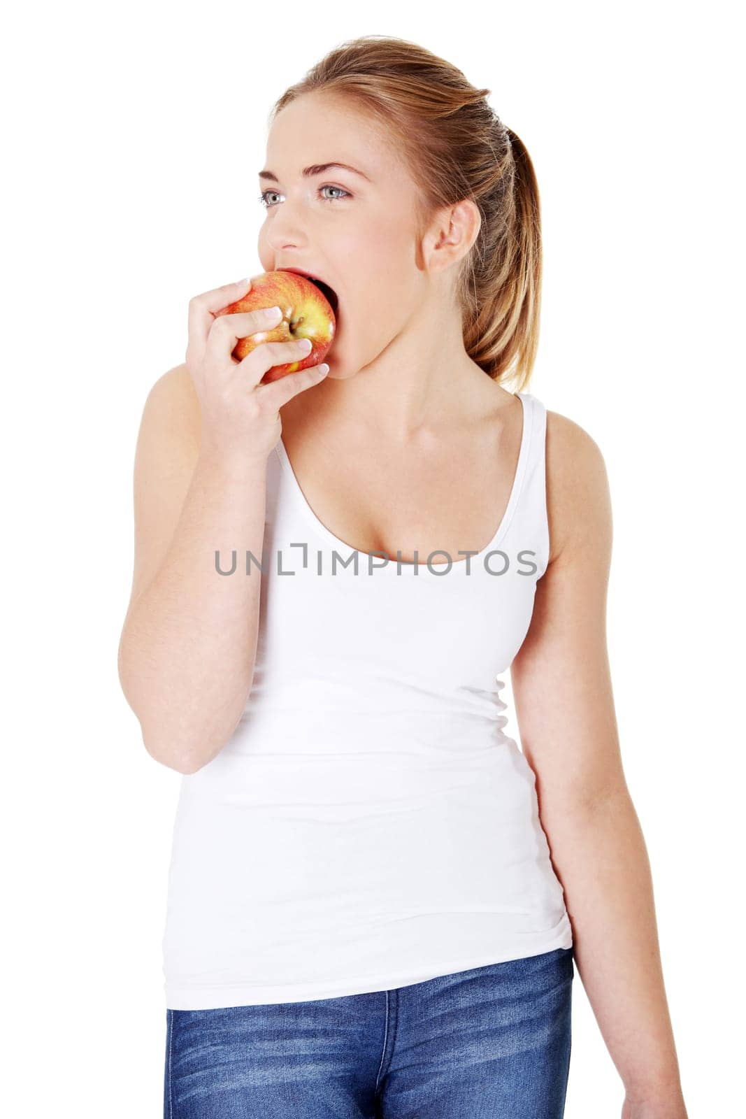Young beautiful woman eating red apple looking towards camera