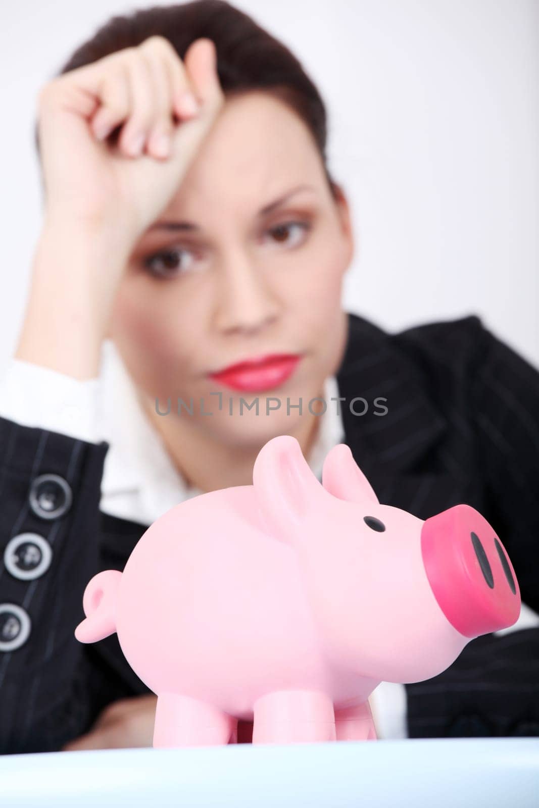 Pretty caucasian businesswoman looking at her piggy bank.