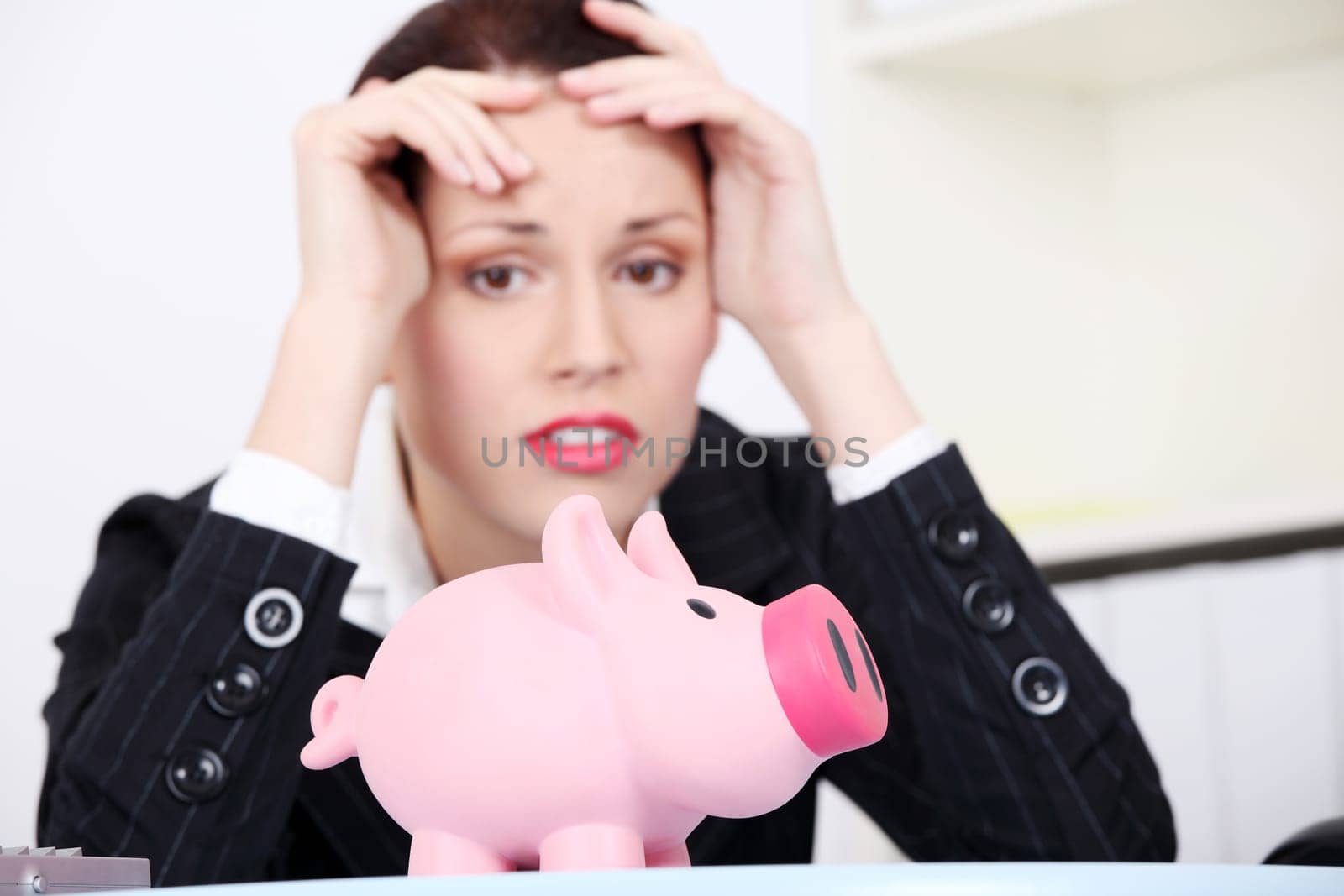 Pretty caucasian businesswoman in depression with piggy bank.