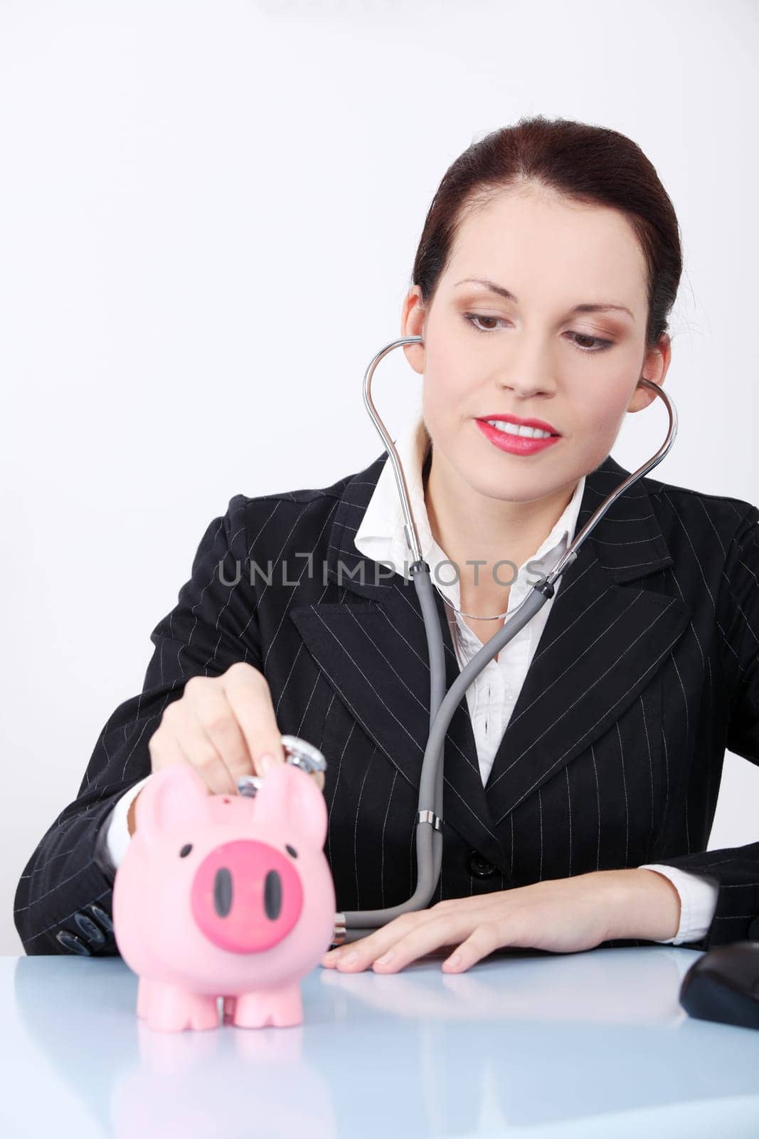 Pretty caucasian businesswoman examining her piggy bank behind the table.