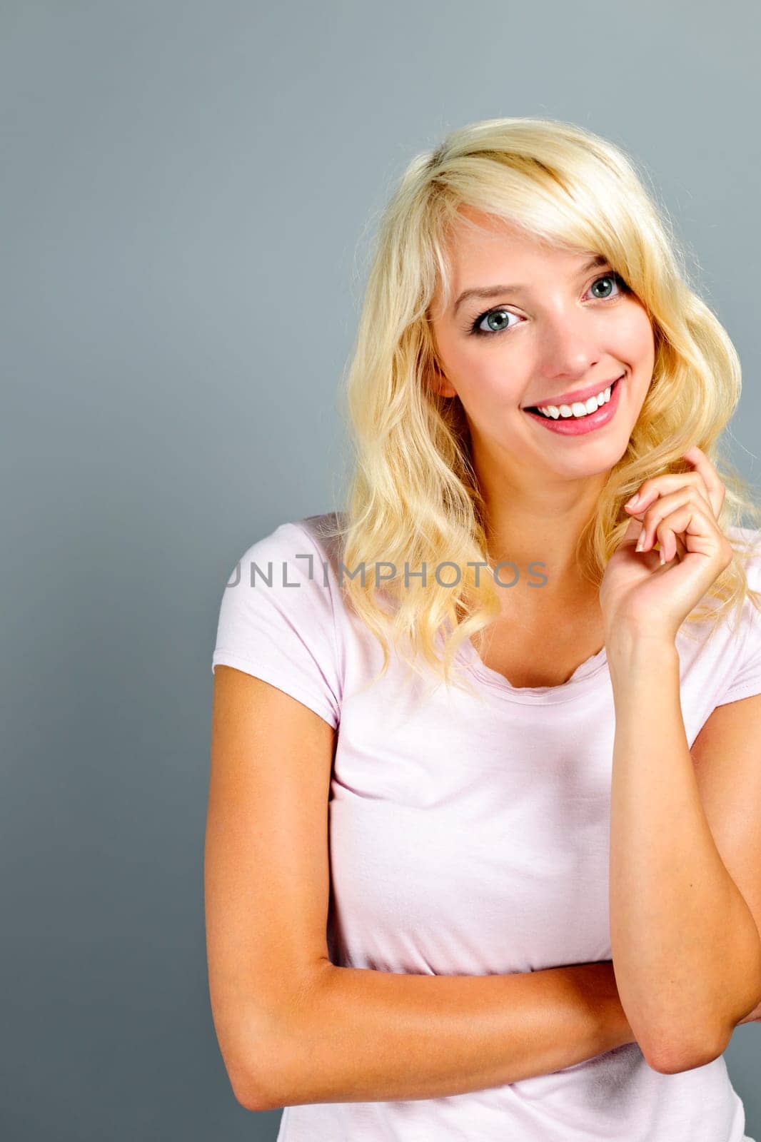 Portrait of smiling young blonde caucasian woman on grey background