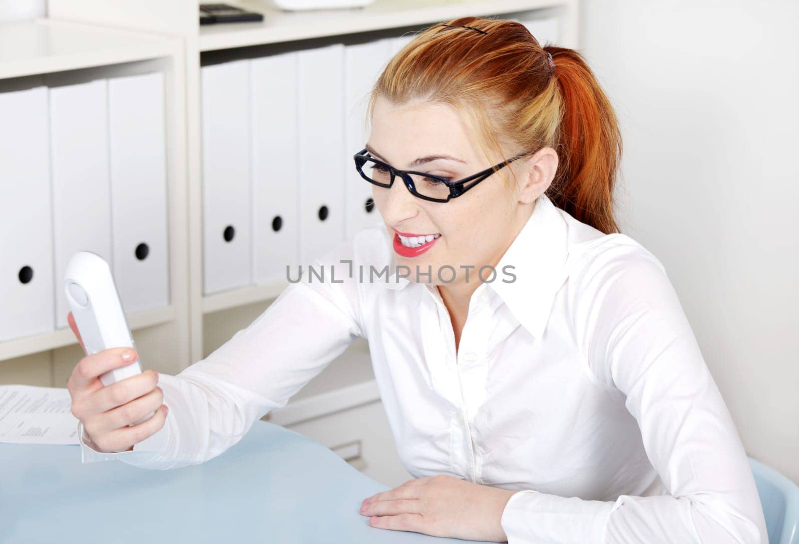 Mad caucasian woman screaming to telephone receiver in the office.