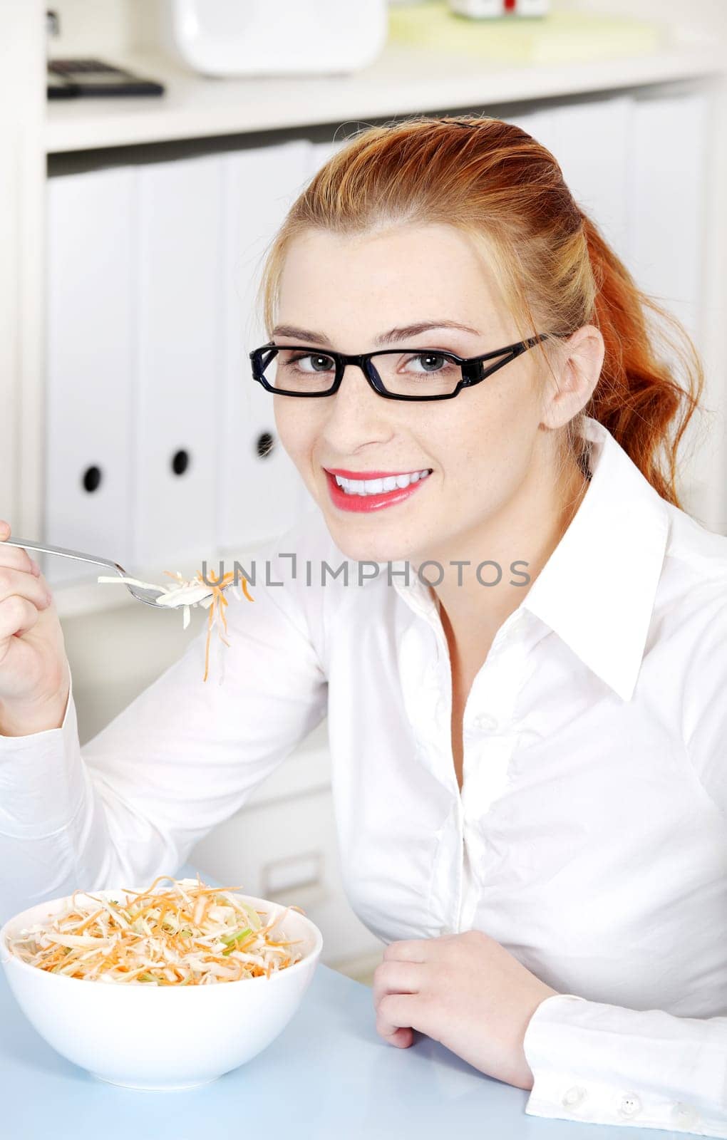 Young businesswomen in glasses eating diet meal in the office.