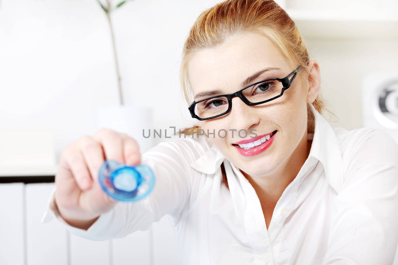 Blonde caucasian businesswoman giving dummy to her child in the office.