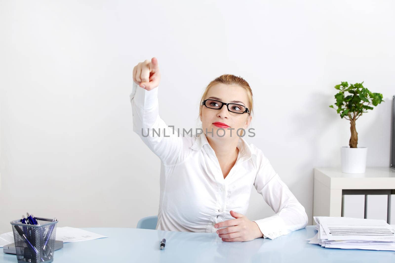 Pretty businesswoman pushing an abstract button in the office.