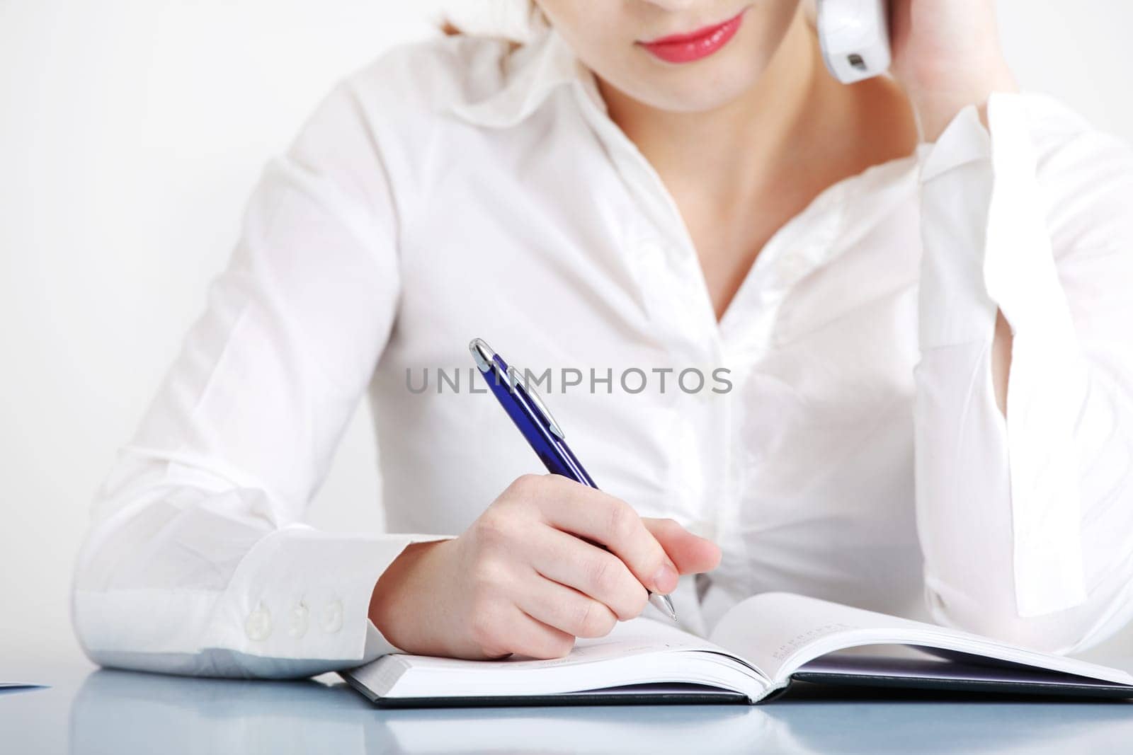 Closeup on talking by the telephone caucasian woman`s writing hand.