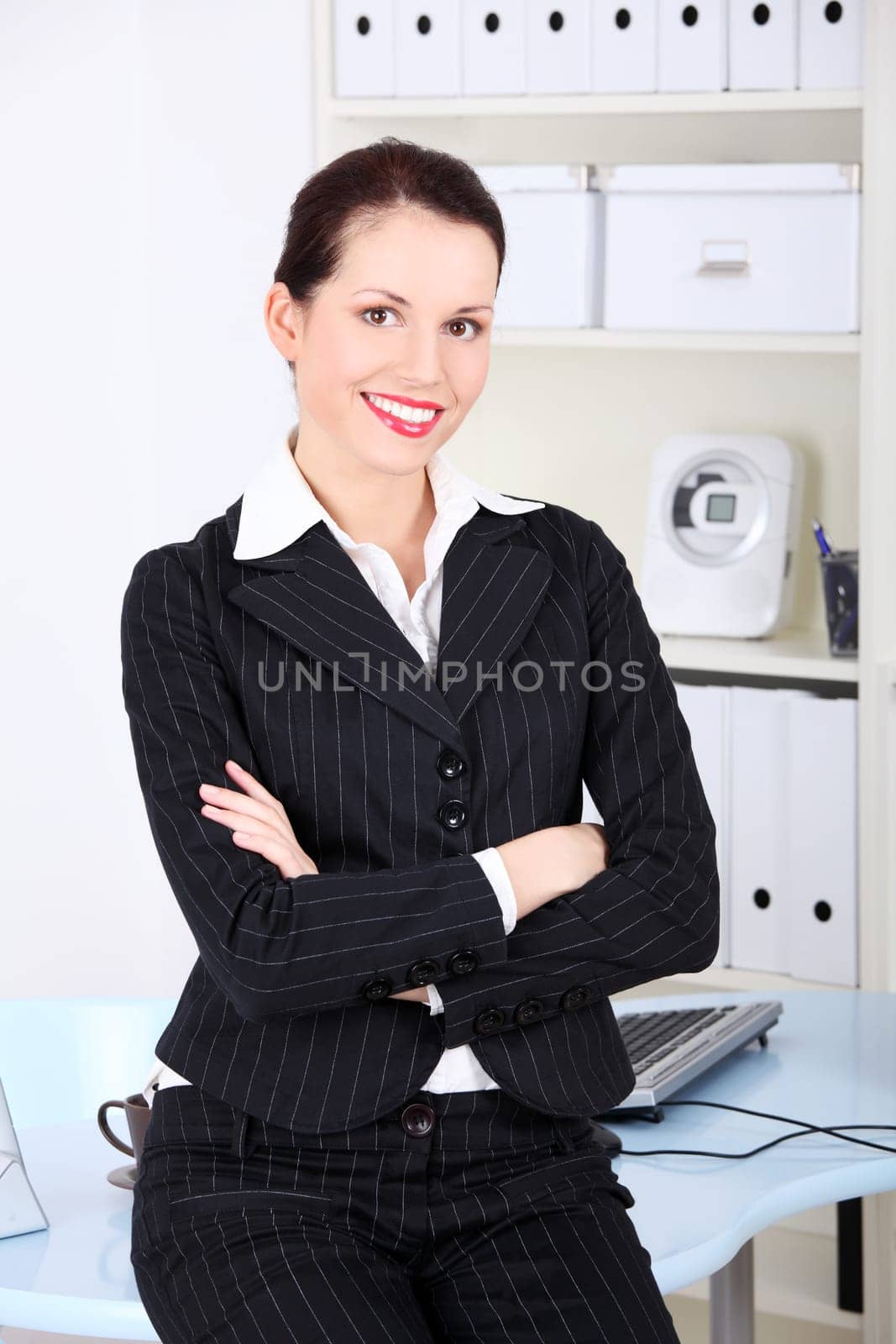 Pretty caucasian businesswoman standing in the office with crossed hands.
