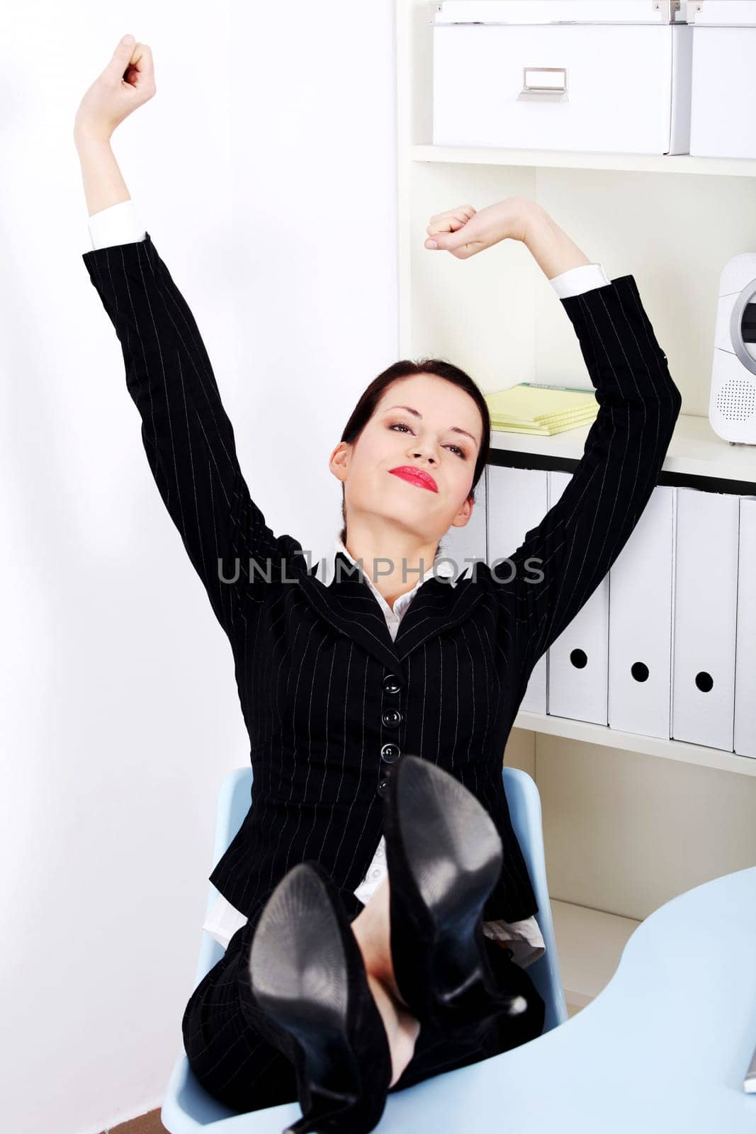 Beautiful caucasian businesswoman with legs laying on the desk stretching in the office.