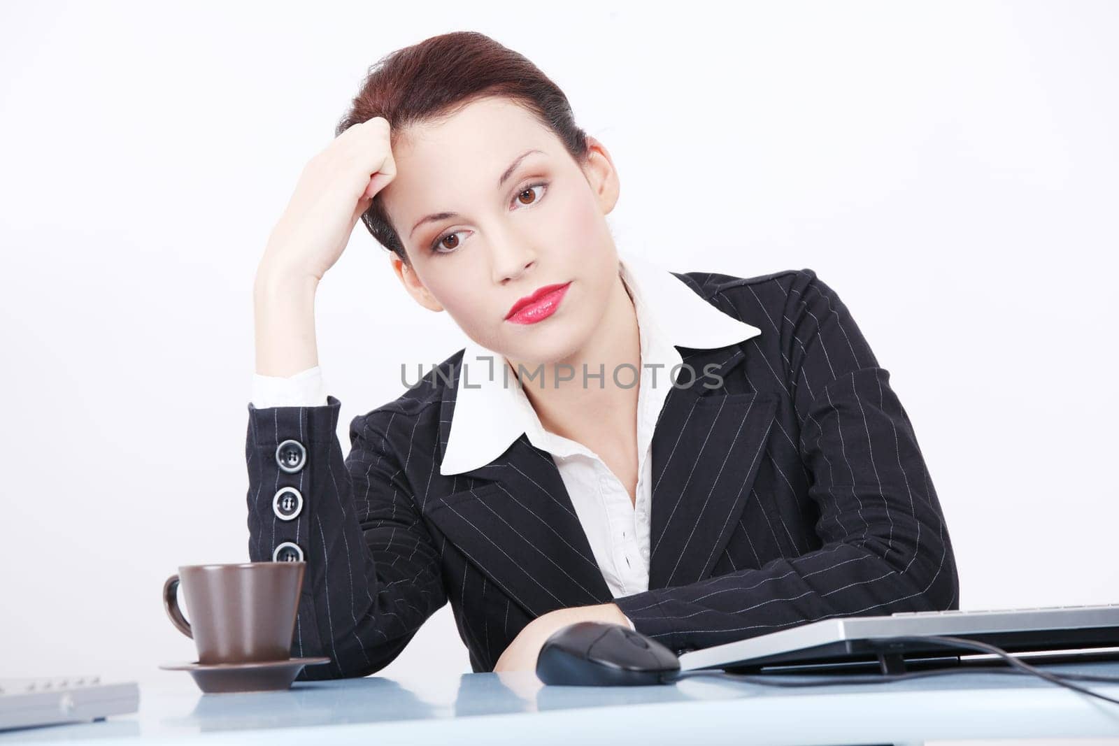 Pretty caucasian thinking businesswoman sitting behind the desk in the office.