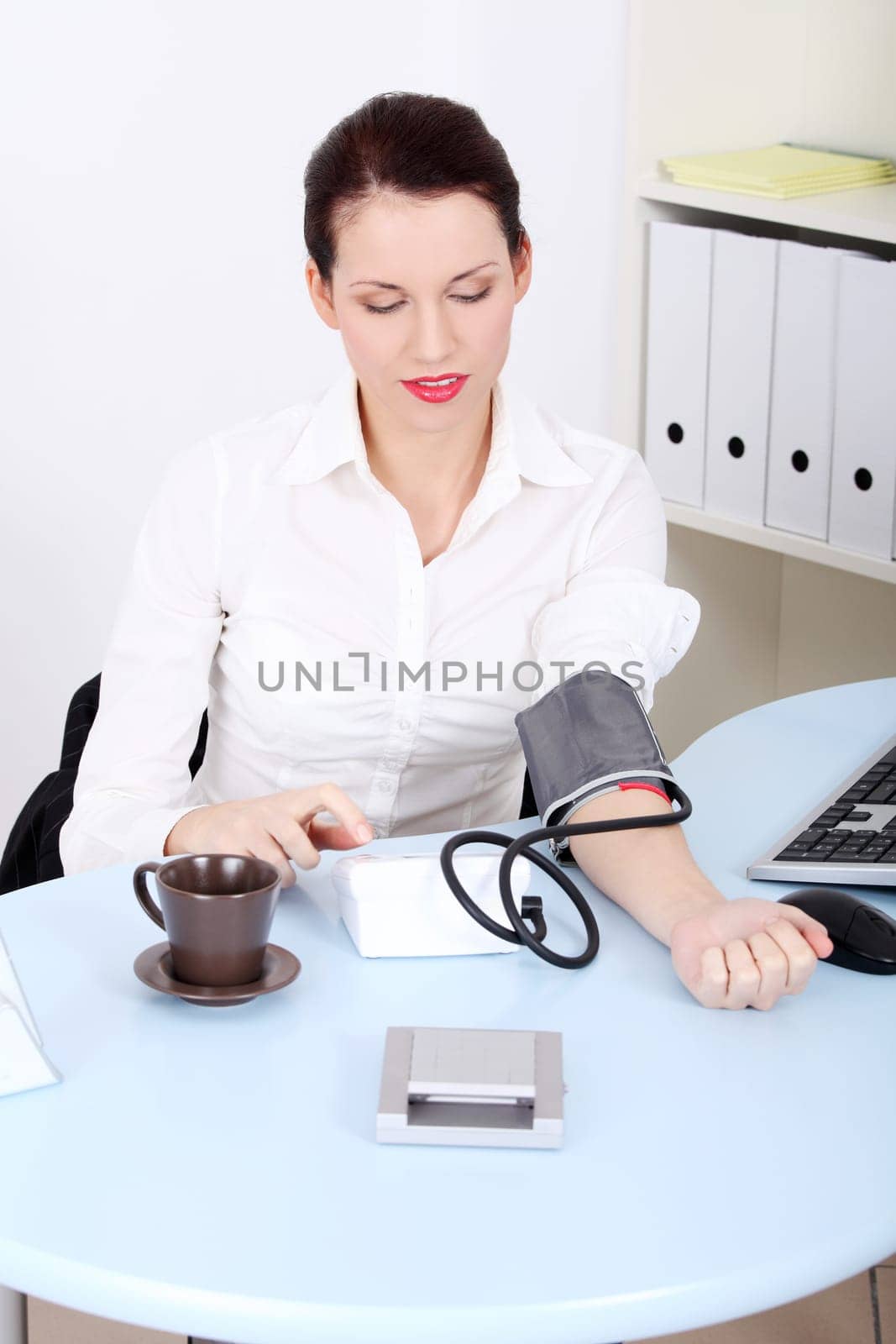 Beautiful caucasian businesswoman measuring her blood pressure in the office.