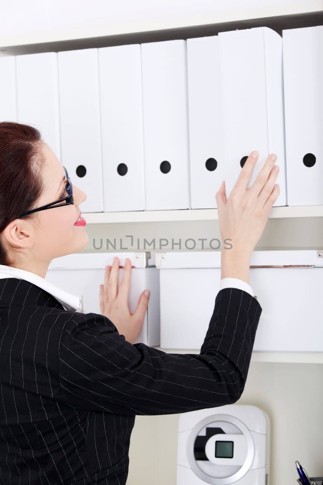 Pretty caucasian businesswoman searching files in the office.