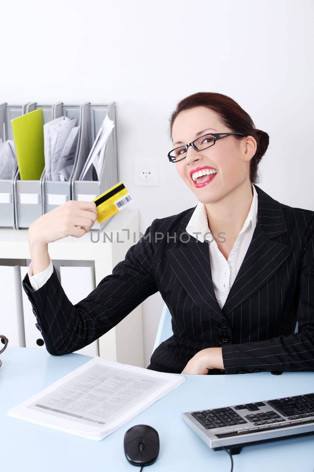 Pretty caucasian happy businesswoman holding credit card in the office.