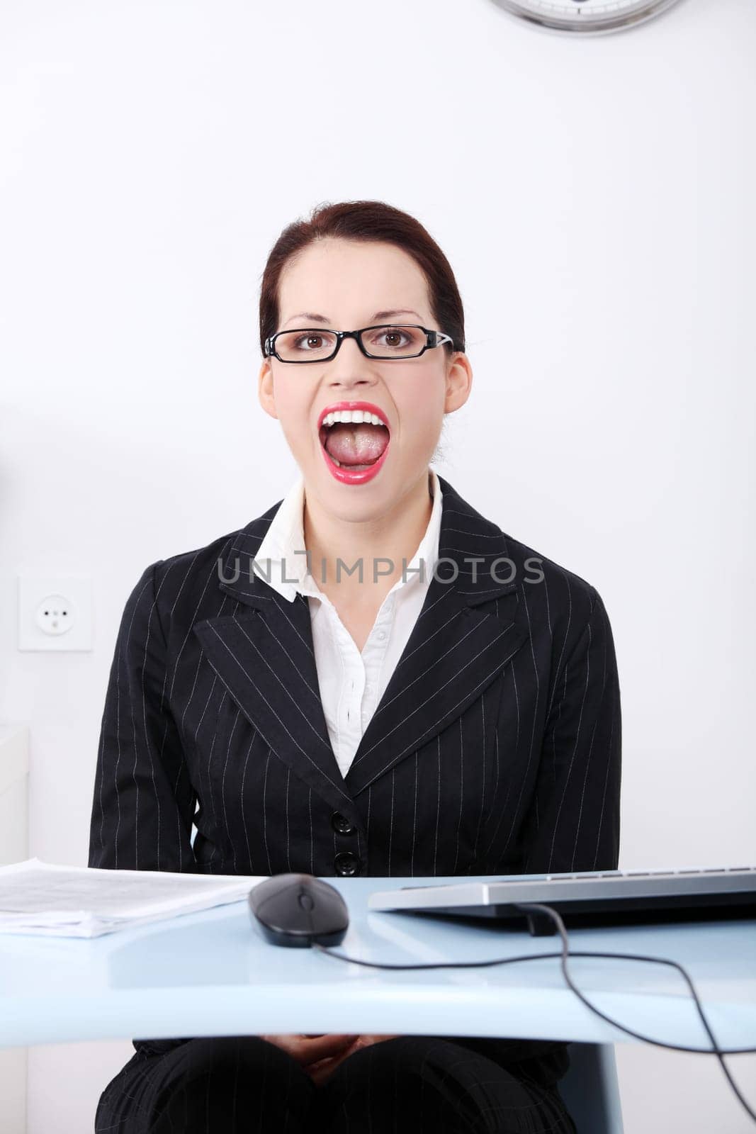 Pretty caucasian screaming businesswoman sitting behind the desk in the office.