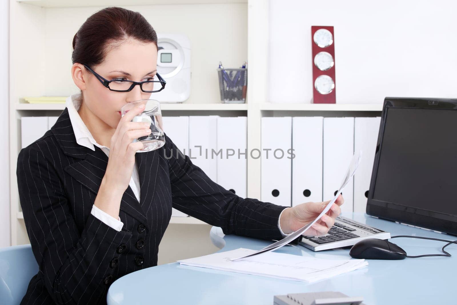 Pretty caucasian businesswoman reading and drinking water.
