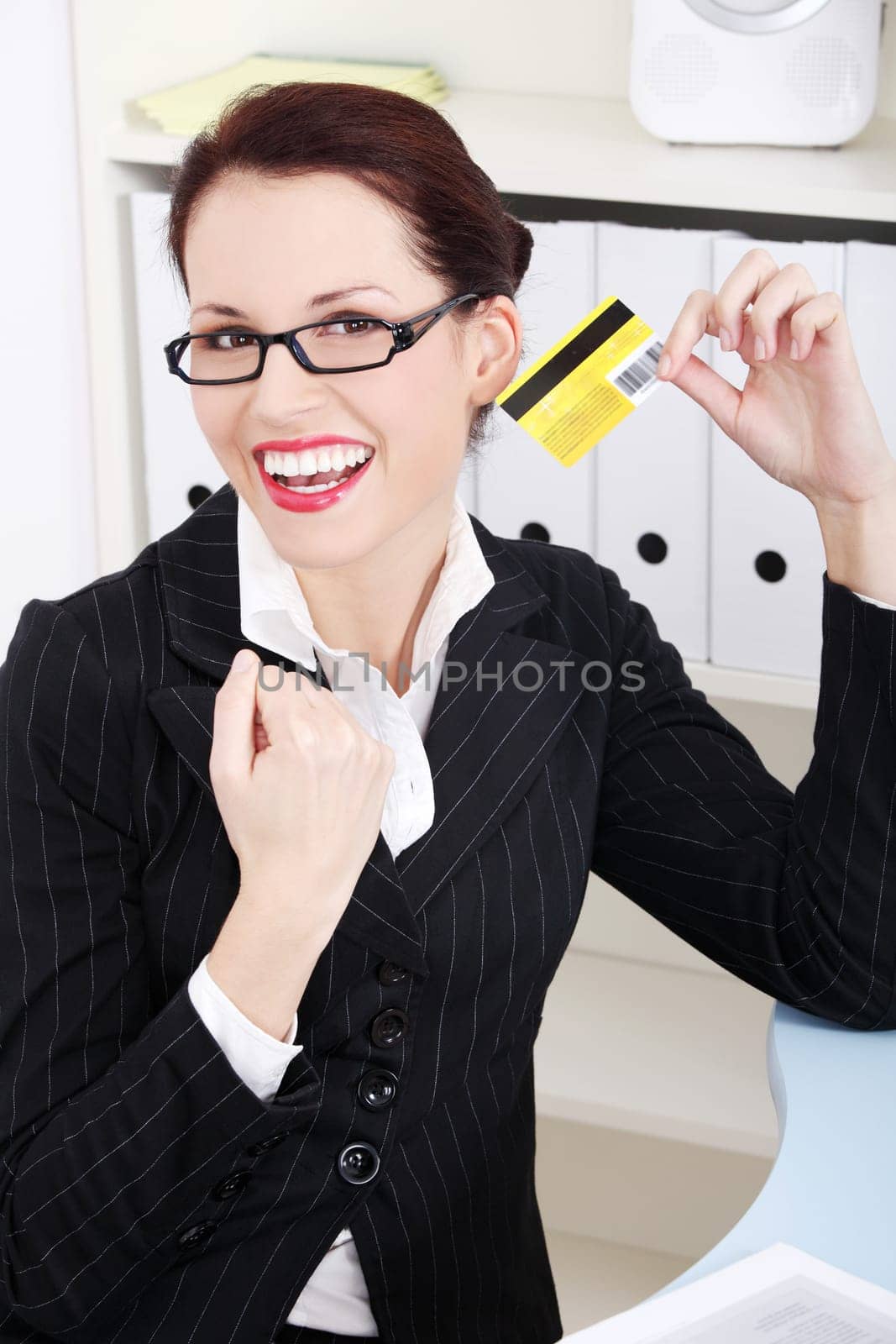 Pretty caucasian happy businesswoman holding credit card in the office.