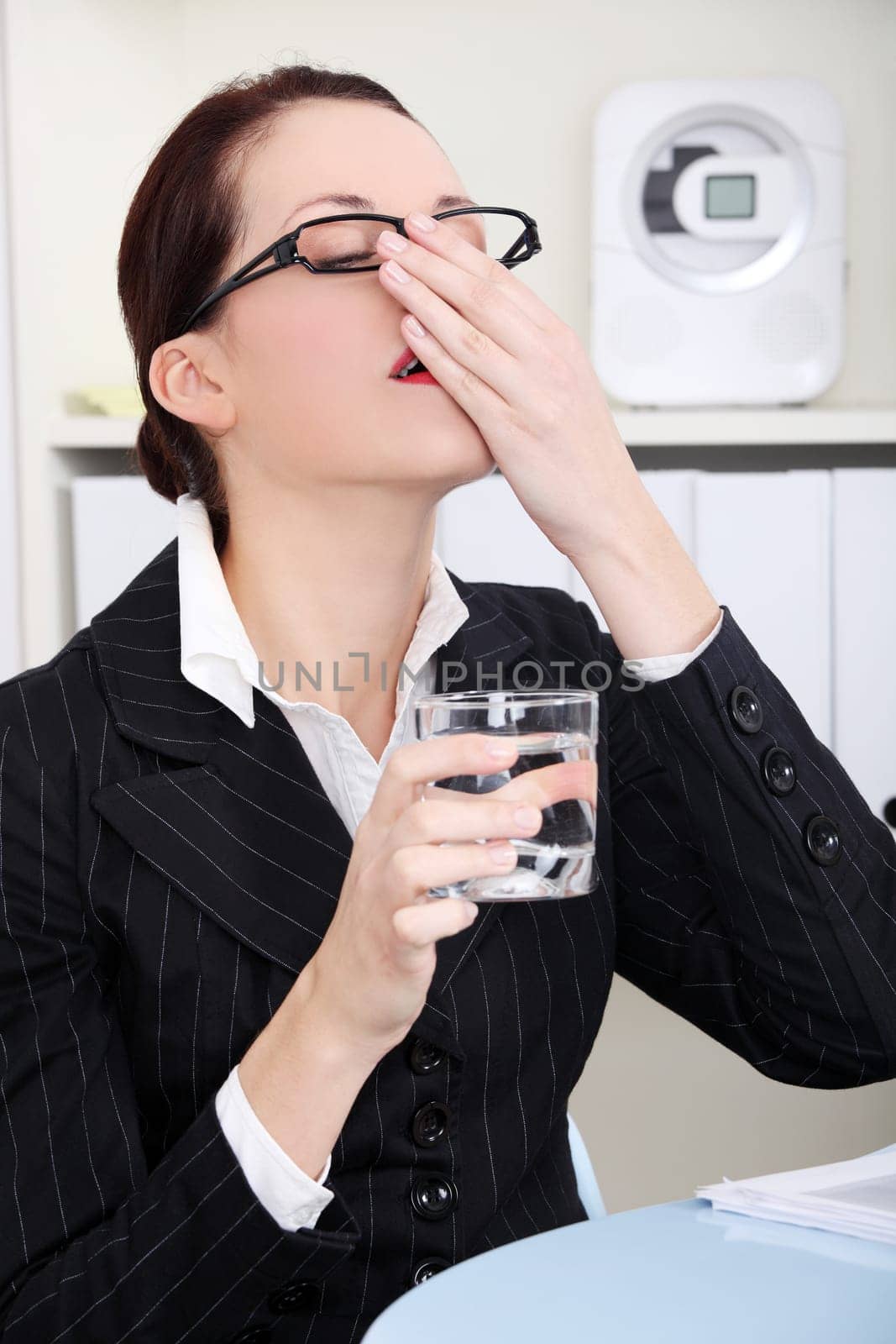 Pretty caucasian businesswoman taking pills in the office.